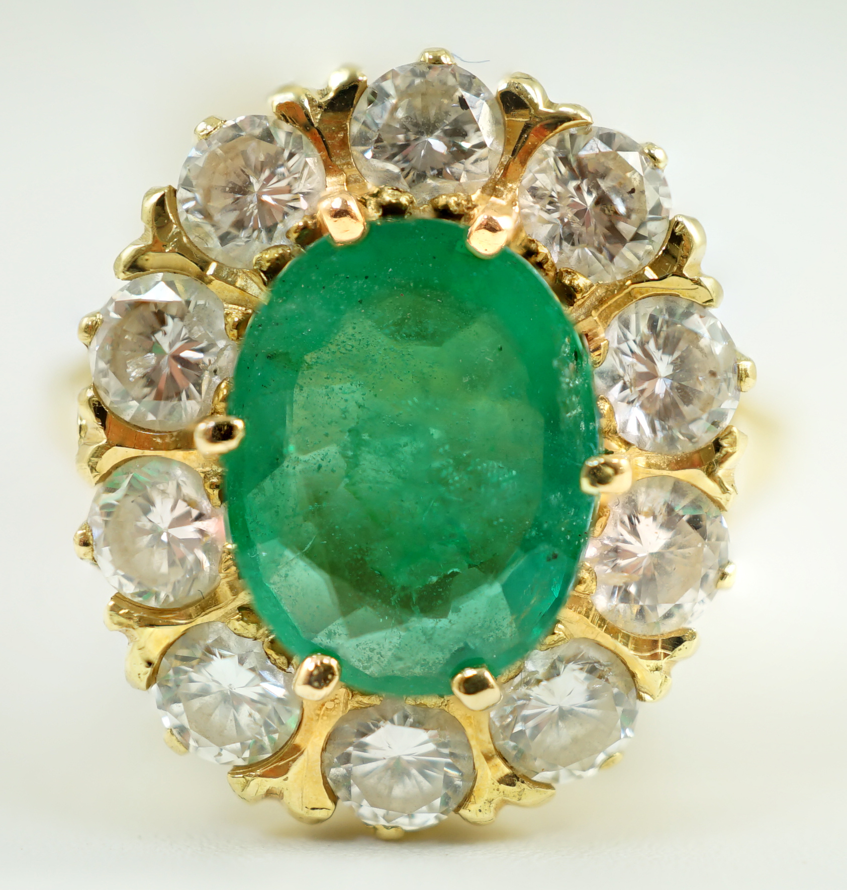 A modern 18ct gold, emerald and diamond set oval cluster ring